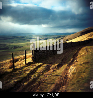 Avec vue sur la lande de la voie agricole à la recherche vers le bas à travers champs avec un ciel orageux à Rushup Edge, Peak District, Angleterre Banque D'Images