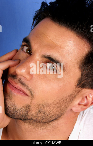 Beau jeune homme de 30 ans avec les cheveux noirs et les yeux bruns portrait sur un fond bleu clair Banque D'Images