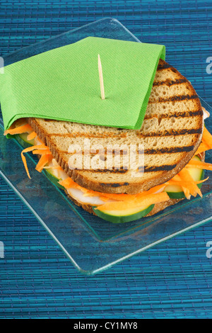 Sandwich à la dinde rôtie julienne de carottes et des tranches de concombre sur une plaque de verre transparent. Focus sélectif. Banque D'Images