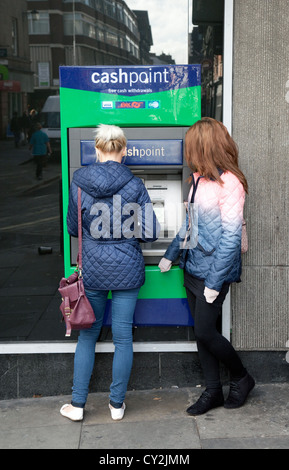 Deux adolescents à percevoir de l'argent à un distributeur de billets ATM Lloyds TSB, UK Banque D'Images