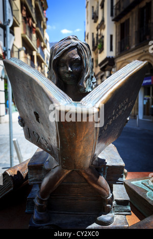 Gros plan de statue en bronze d'une fille assise sur une pile de livres lisant un livre dans la rue Banque D'Images