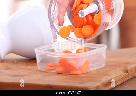 Les carottes tranchées dans un mini robot de cuisine Banque D'Images