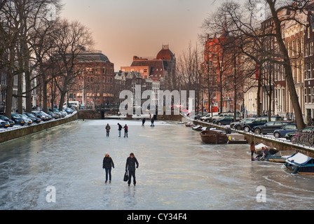 Les gens patiner sur les canaux gelés d'Amsterdam sur une soirée d'hiver Banque D'Images