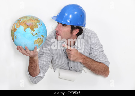 Builder avec colère pointant à globe Banque D'Images