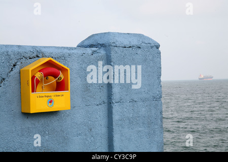 Ringbouy sur un mur à Dun Laoghaire Dublin Irlande voile au loin sur la mer Banque D'Images