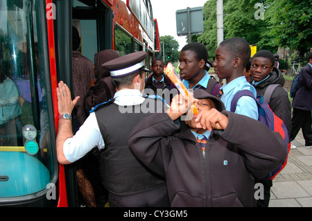 Rowdy mais smart collégiens se font concurrence pour obtenir sur un bus. Un agent de soutien communautaire permet de garder le contrôle et protège le public. Banque D'Images