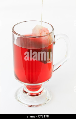 Tasse en verre de thé avec un sachet de thé sur un fond blanc. UK Banque D'Images