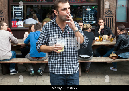 Un homme fume une cigarette à l'extérieur du Cat et de mouton Public House à Broadway Market, London Fields, London, East London Banque D'Images