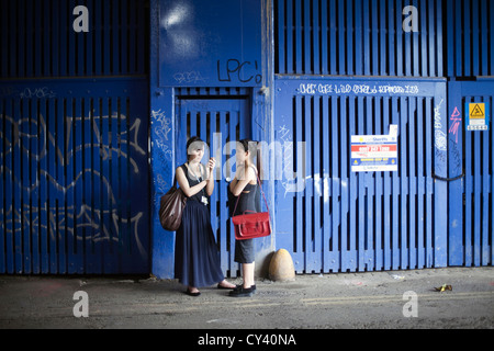 Deux touristes japonais parler dans la rue sous le pont de chemin de fer, Shoreditch Banque D'Images