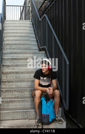 Un jeune homme écoute de la musique sur le casque les étapes de l'Boxpark - un "pop up mall" composé de vieux contenants d'expédition Banque D'Images