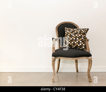 Meubles anciens meubles fauteuil avec coussin contre mur blanc Banque D'Images