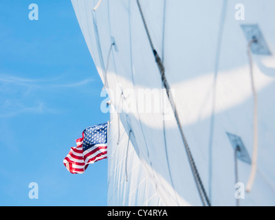 USA (Maine), Camden, voiles blanches et drapeau américain contre le ciel bleu Banque D'Images