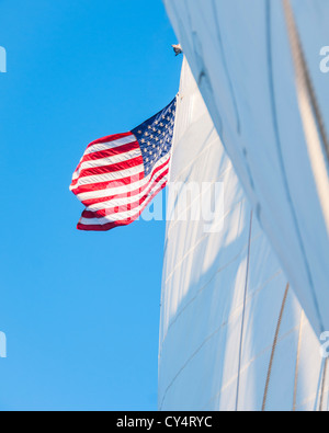 USA (Maine), Camden, voiles blanches et drapeau américain contre le ciel bleu Banque D'Images