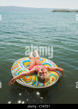 USA, Utah, Garden City, girl (4-5) flottant sur l'eau sur l'anneau gonflable et de rire Banque D'Images