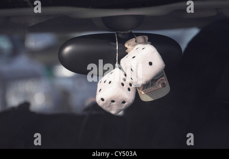 Fluffy dice et d'assainisseur d'air accroché au rétroviseur intérieur de la voiture. Banque D'Images