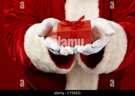 Photo de Père Noël les mains gantées tenant coffret rouge Banque D'Images