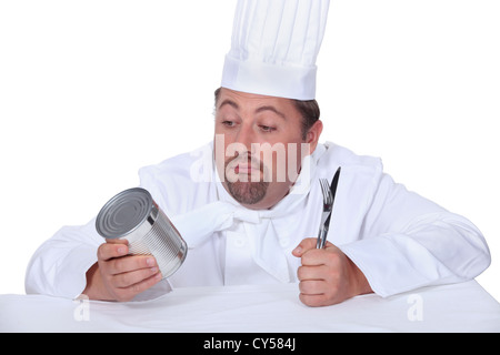 Cook holding tin et couverts, studio shot Banque D'Images