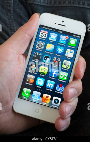 Libre de man holding nouvel iPhone 5 smart phone montrant l'écran avec de nombreuses applications Banque D'Images