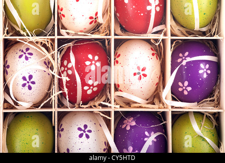 Les oeufs de Pâques peints de couleurs dans une boîte en bois Banque D'Images