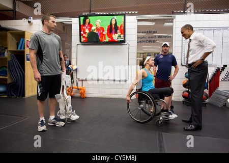 Le président américain Barack Obama parle avec des athlètes paralympiques au centre de formation olympique américaine le 9 août 2012 à Colorado Springs, Colorado. Diffusion de la médaille d'or pour la cérémonie Olympique US women's soccer team joue sur le plat à l'arrière-plan. Banque D'Images