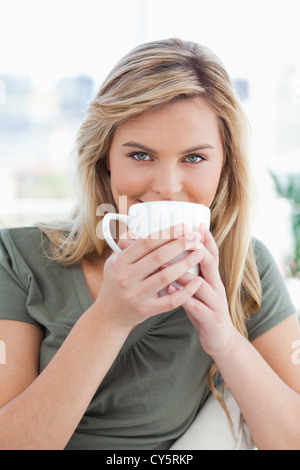 Close up, femme avec un mug a tenu jusqu'en face de sa bouche et de regarder droit devant Banque D'Images