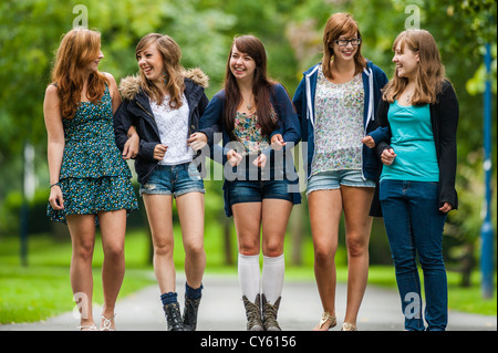 Un groupe de cinq jeunes adolescents 5 british english welsh adolescentes adolescents amis marchant ensemble dans les bras l'extérieur UK Banque D'Images