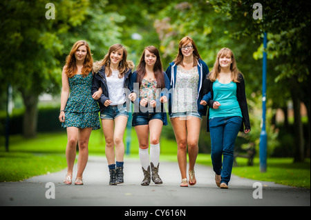 Un groupe de cinq jeunes adolescents 5 british english welsh adolescentes adolescents amis marchant ensemble dans les bras l'extérieur UK Banque D'Images