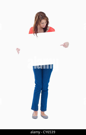 Smiling adolescent holding a blank poster en pointant sur elle Banque D'Images