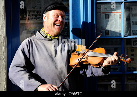 Busker rue de jouer d'un instrument de musique et le divertissement du grand public pour de l'argent dans les rues étroites de Whitby. Banque D'Images