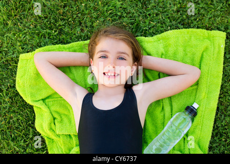 Enfants girl lying on détendue serviette sur l'herbe vert bouteille avec de l'eau en maillot de bain Banque D'Images