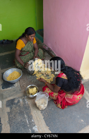 Les femmes indiennes le mélange de Jagré Dal mélange avec une meule en pierre pour faire des bonbons festival Dasara dans un village de l'Inde rurale. L'Inde Banque D'Images