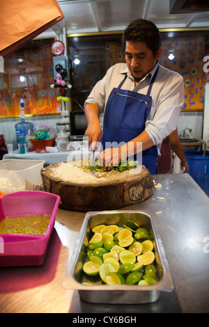 L'homme préparer les oignons et la coriandre pour être servi avec Carnitas tacos au marché en Jamaïque à Mexico DF Banque D'Images