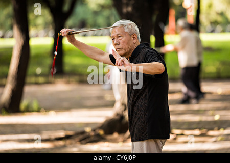 Un vieil homme chinois arts martiaux pratiques épée exercice tôt le matin au Temple du Ciel à Beijing au cours de l'été Parc Banque D'Images