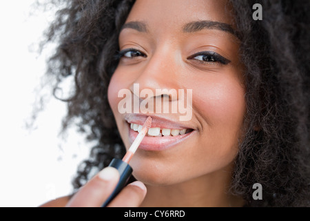 Young smiling woman making-up lors de l'utilisation d'un applicateur brillant à lèvres Banque D'Images