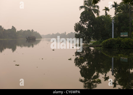 Barge à riz touristique passant réflexions sur la côte ouest (canal navigable National No 3) au lever du soleil, Kanjippadom, près de Alappuzha (Alleppey), Kerala, Inde Banque D'Images