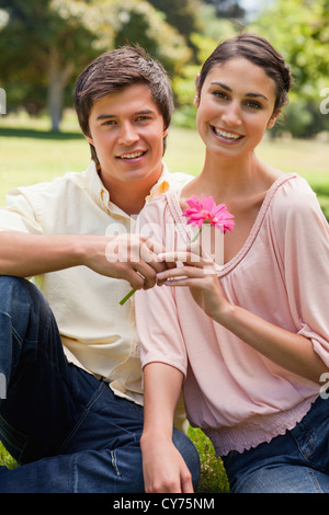 Homme donnant à une fleur à une femme, qui tous deux aller de l'avant Banque D'Images