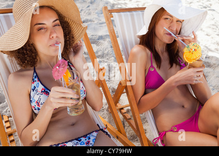 Les jeunes femmes en sirotant leurs cocktails exotiques sur la plage Banque D'Images