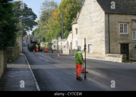 Le resurfaçage de la route à Bibury Gloucestershire Banque D'Images