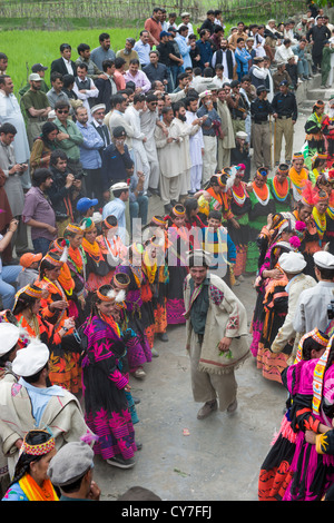 Kalash l'homme et de la femme à danser à l'Anish Brun Village Charso (danse), surveillées par des foules d'hommes musulmans, Kalash Joshi (Fête du Printemps), la vallée de Bumburet, Chitral, Khyber-Pakhtunkhwa, Pakistan Banque D'Images