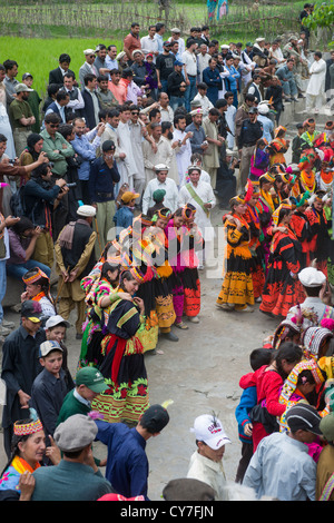 Kalash l'homme et de la femme à danser à l'Anish Brun Village Charso (danse), surveillées par des foules d'hommes musulmans, Kalash Joshi (Fête du Printemps), la vallée de Bumburet, Chitral, Khyber-Pakhtunkhwa, Pakistan Banque D'Images