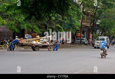 Travailleurs vietnamiens pousser le panier de travail sur une route très fréquentée à Hai Phong Vietnam Banque D'Images