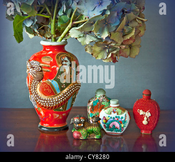 Composition du petit vieux Flacons à parfum chinois et japonais avec un vase de fleurs d'hortensias sur une table en bois Banque D'Images