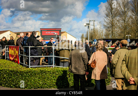 Les gens de monde autour de la course de chevaux à l'écoute de forcecasters tips Banque D'Images