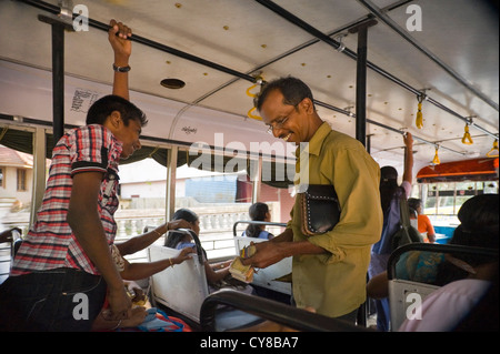 Vue intérieure horizontale d'un bus public au Kerala avec un conducteur la collecte des billets. Banque D'Images