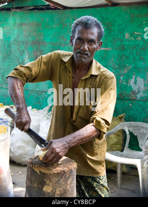Portrait vertical d'un indien de la préparation coco à vendre avec un couteau tranchant. Banque D'Images