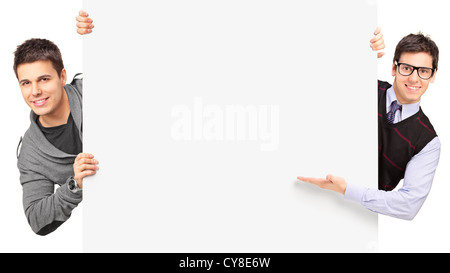 Les jeunes gars posant derrière un panneau blanc isolé sur fond blanc Banque D'Images