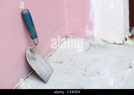 Truelle de maçonnerie sur un mur de béton inachevé Banque D'Images