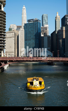 Un taxi jaune eau de Chicago se déplace le long de la rivière Chicago avec la ville en arrière-plan. Banque D'Images