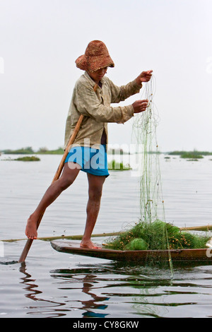 Le Myanmar, Birmanie. Préparer son filet pêcheur ethnie Intha, en équilibre sur une jambe, dans le style habituel de Lac Inle, l'État Shan. Banque D'Images