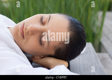 Femme couchée avec les mains derrière la tête à l'extérieur Banque D'Images